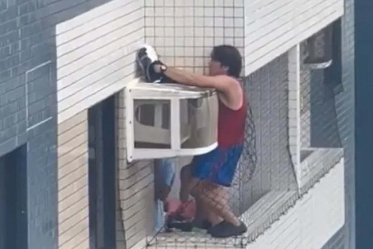 Homem se pendura em varanda para resgatar gata em caixa de ar-condicionado