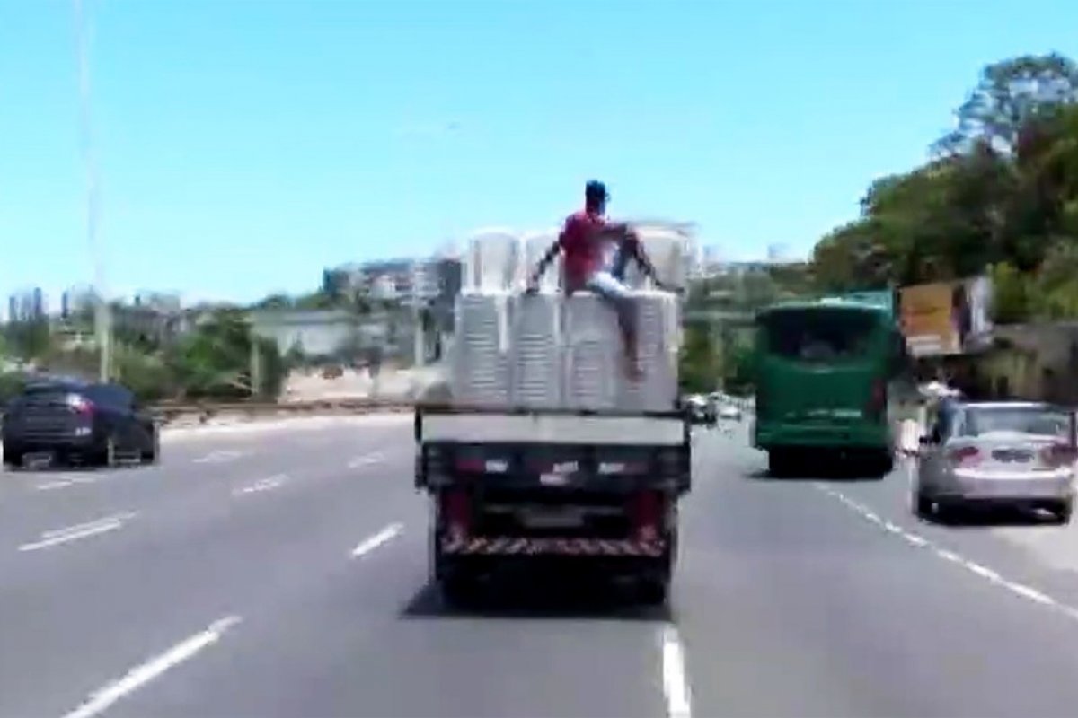 Homem é transportado em cima de 'montanha' de cadeiras, em carroceria de caminhão 